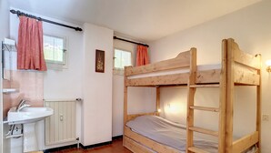 Ein Schlafraum mit Etagenbett aus Holz, einem Waschbecken und einem Fenster mit Vorhängen.