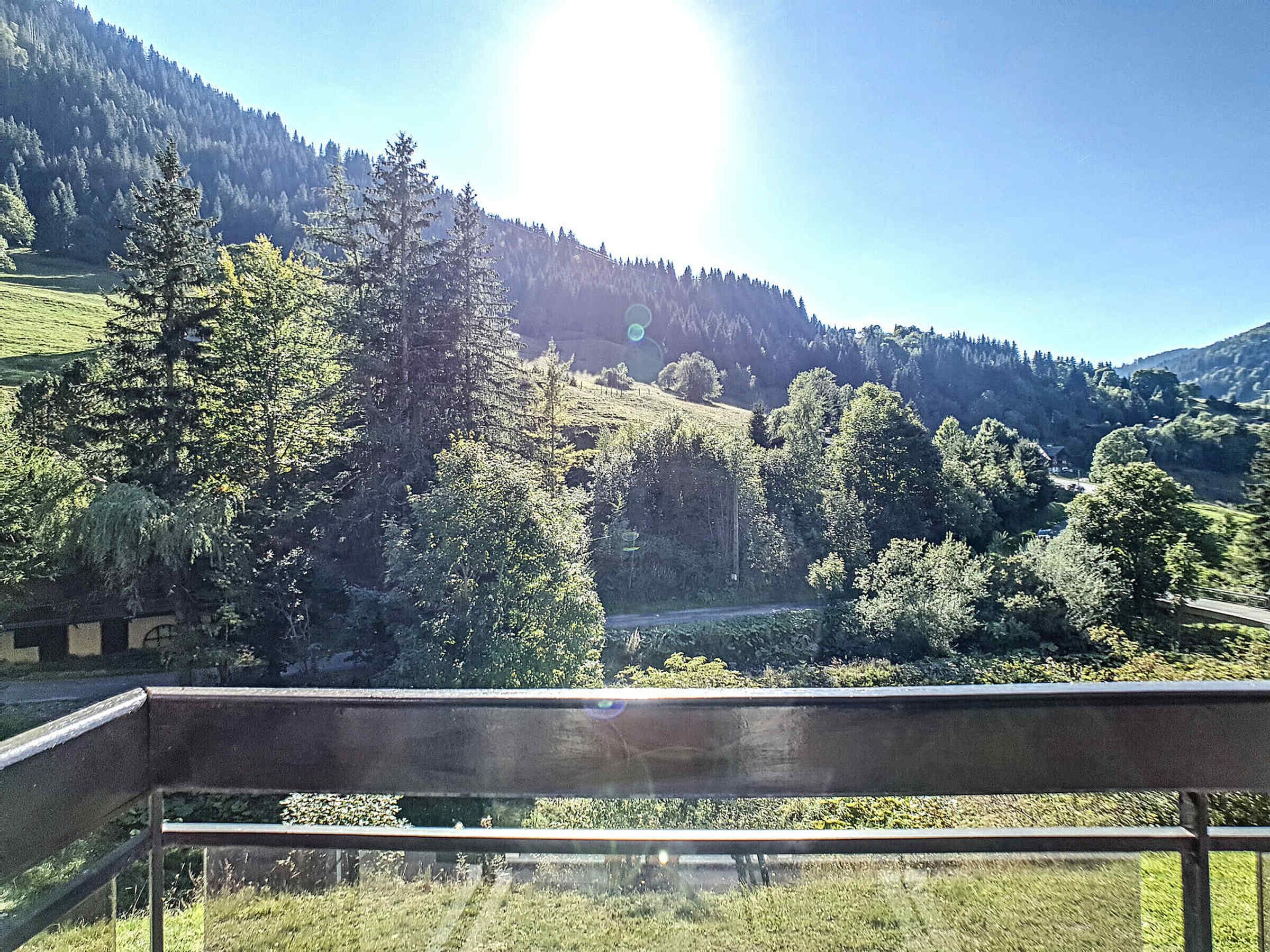 Een prachtig uitzicht vanaf een balkon, met zicht op een vallei vol bomen en heuvels.