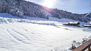 A snow-covered landscape with a cabin and a wooden deck.