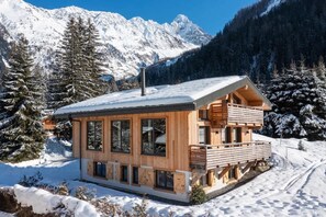 A wooden cabin with large windows, a balcony, and a snow-covered mountain backdrop. - Luxury Ski In Ski Out 4 Bed Chalet at Grands Montets, Argentiere (Chamonix-Mont-Blanc)