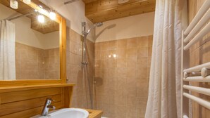 A bathroom with a wooden vanity, a white sink, a shower with a glass door, and a bathtub.