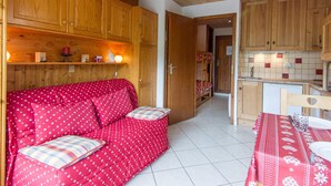 A cozy room with a red sofa, wooden cabinets, and a tiled floor.