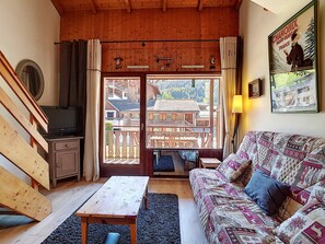 Relax in this serene room with a view of traditional buildings, featuring a sofa, bench, and table for dining or relaxation.