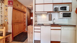 Cocina compacta con armarios de madera, microondas, tostadora y lavavajillas.