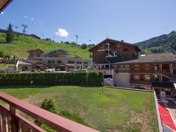 Surrounded by trees and mountains, this resort offers a serene hillside setting with a grassy area and various buildings.