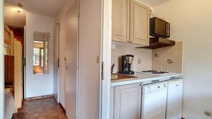 A compact kitchen with white cabinets, a coffee maker, and a dishwasher.