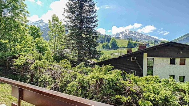 A mountain cabin with a wooden deck and a view of snow-capped mountains.