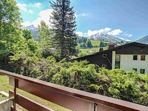 A mountain cabin with a wooden deck and a view of snow-capped mountains.