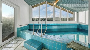 An indoor swimming pool with clear glass walls, blue tiled steps, and metal ladders. - Lovely holiday home with pool, spa and sauna, only 200 meters from the North. (Harboøre)