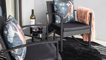 A seating area with two chairs and a table, a bottle of wine, and a blanket.