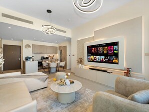 A modern living room with a flat-screen TV, a dining area, and a kitchen.