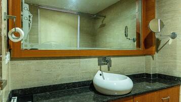 A bathroom with a white sink, a mirror, and a shower.