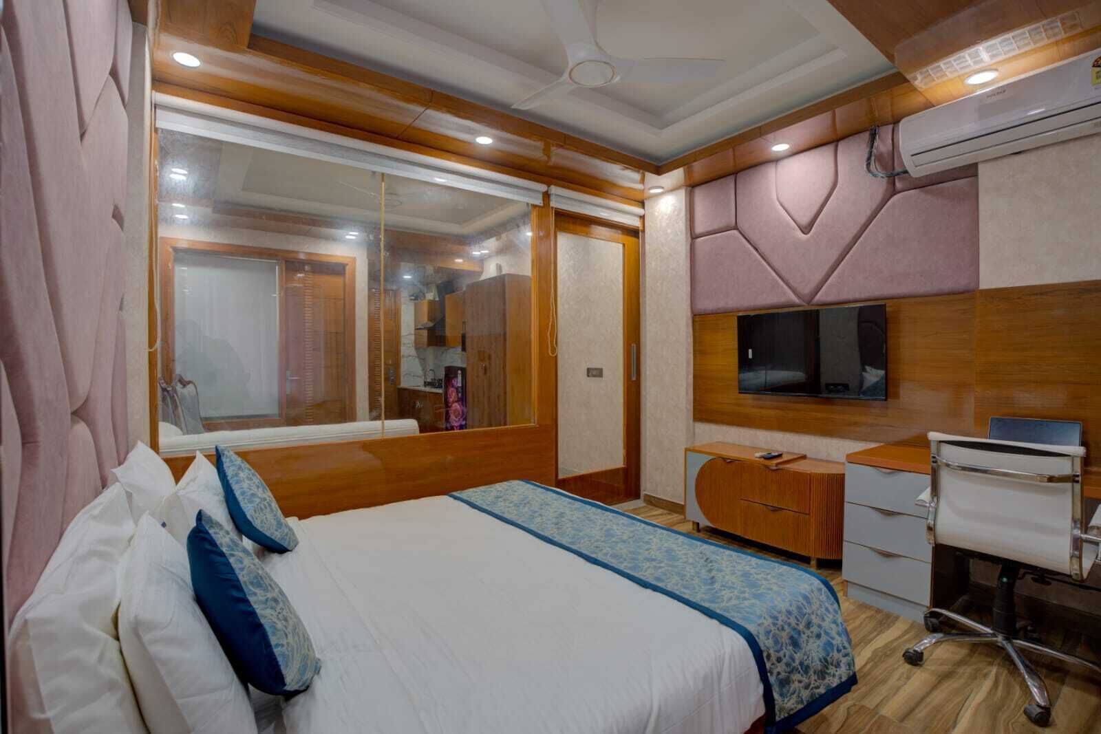 A bedroom with a large bed, a desk, and a TV.