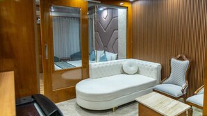 Ein modernes Zimmer mit einem weißen Sofa, einer Holzvertäfelung an der Wand und einer Schiebertür zum Spiegelkleiderschrank.