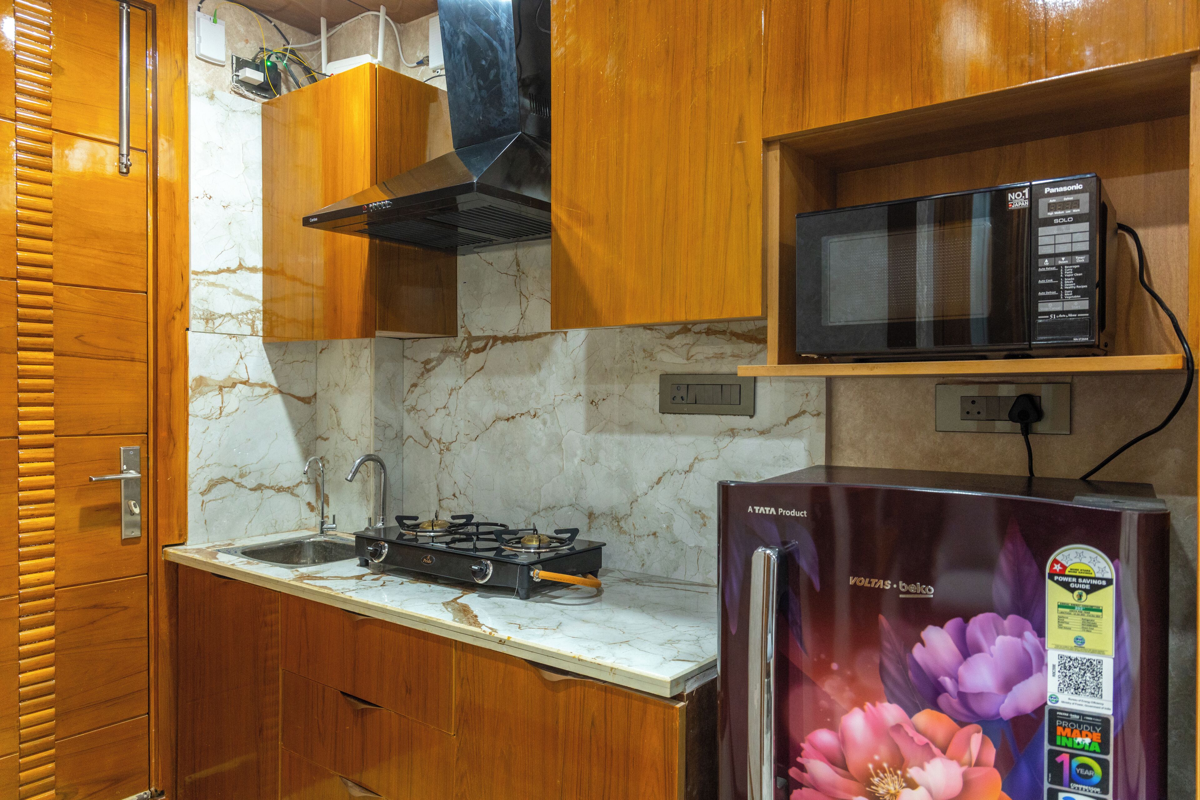 Una cocina con armarios de madera, estufa a gas, microondas y refrigerador.