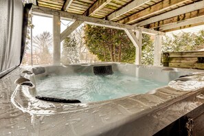 A hot tub with a wooden deck and a view of trees.