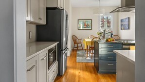 Una cocina moderna con armarios grises, un refrigerador negro y un comedor con mesa y sillas amarillas.