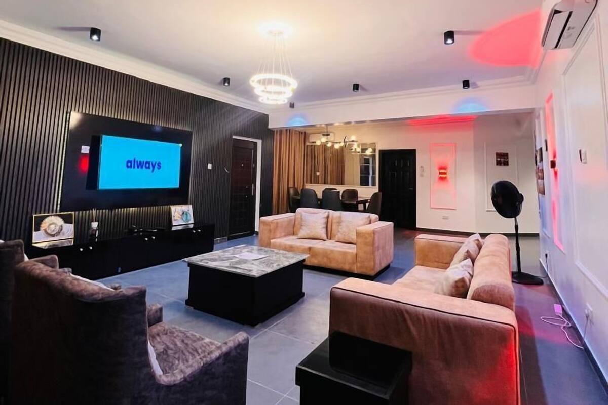 Un salon moderne doté d’un téléviseur à écran plat, de canapés, d’une table basse et d’un éclairage d’ambiance.