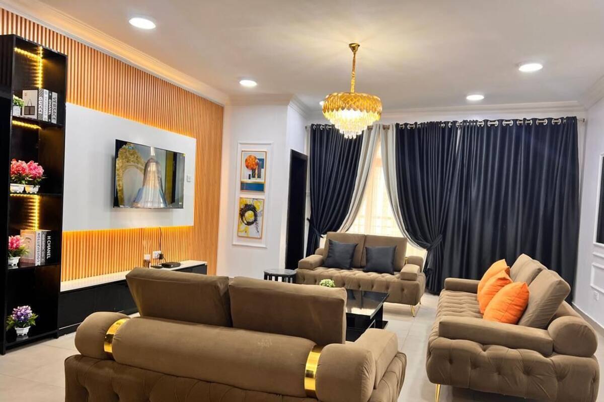 Un salon moderne avec un ensemble de canapés, un téléviseur fixé au mur et une étagère décorative.
