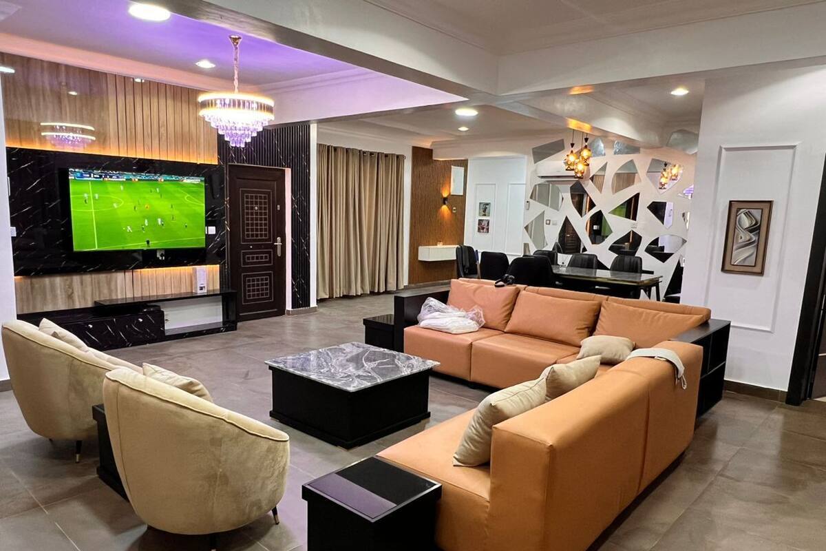 Un salon moderne doté d’un grand téléviseur à écran plat, de sièges confortables et d’un mur décoratif.