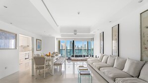 Una sala de estar moderna con comedor, un sofá y vistas al horizonte de la ciudad.