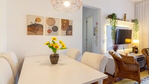 A modern living room with a white dining table, wicker chairs, a white sofa, and a TV on a stand. - 4 minutes from Arcos da Lapa | SR1502 (Rio de Janeiro)