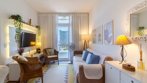 A modern hotel room with a flat-screen TV, a sofa, a dining table, and a window with a view of a building. - 4 minutes from Arcos da Lapa | SR1502 (Rio de Janeiro)