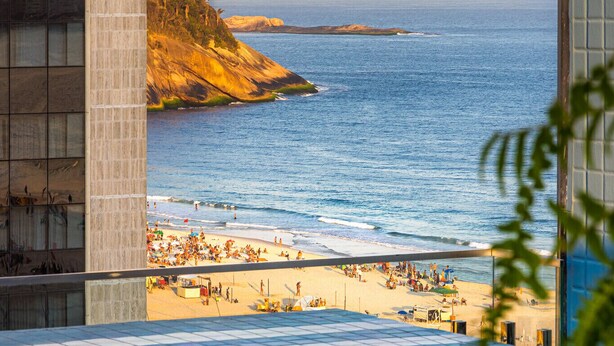 Une piscine à débordement offrant une vue sur une plage et des montagnes.