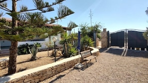 A landscaped garden with a stone wall, a bench, and various plants. - Residence Lo Zodiaco (Lampedusa)