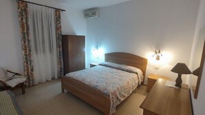 A bedroom with a wooden bed, a nightstand, a lamp, a wardrobe, and a chair. - Residence Lo Zodiaco (Lampedusa)
