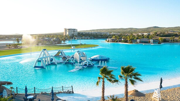 Une grande piscine extérieure dotée de toboggans et d’un espace aménagé comme une plage.