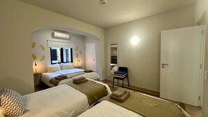 A hotel room with two beds, a desk, a chair, a wardrobe, and a mirror. - Vilanova by Check-in Portugal (Albufeira)