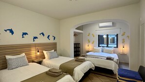 A hotel room with two beds, a wooden headboard, a wall with dolphin decals, a window with shutters, and a small desk with a lamp. - Vilanova by Check-in Portugal (Albufeira)