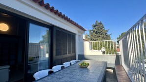 A patio with a table and chairs, a large window, and a view of trees and a fence. - Vilanova by Check-in Portugal (Albufeira)