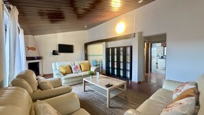 A spacious living room with a white sofa set, a coffee table, and a TV mounted on the wall. - Vilanova by Check-in Portugal (Albufeira)