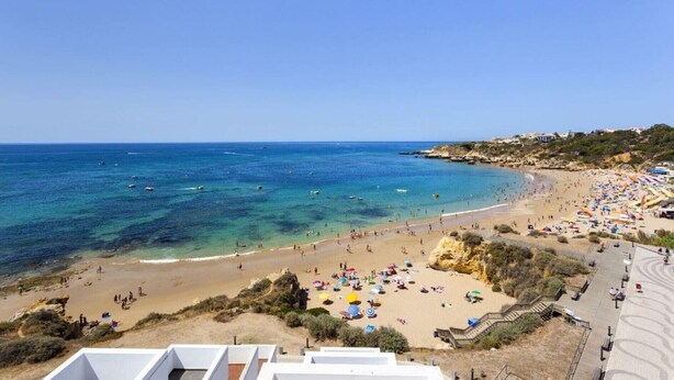 A beach with clear blue waters, sandy shores, and a few boats. - Vilanova by Check-in Portugal (Albufeira)