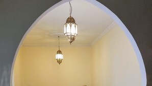 Une chambre à coucher comprenant un lit, une table ronde en bois, un canapé et deux lampes fixées au mur.