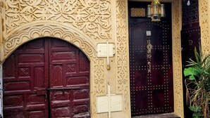 Une entrée d’immeuble dotée de deux grandes portes, l’une rouge et l’autre noire, toutes deux ornées de sculptures complexes et de motifs métalliques.