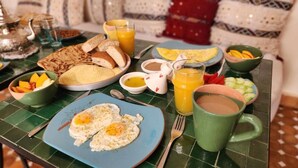 Une table de petit-déjeuner avec des œufs, des toasts, des fruits et des boissons.