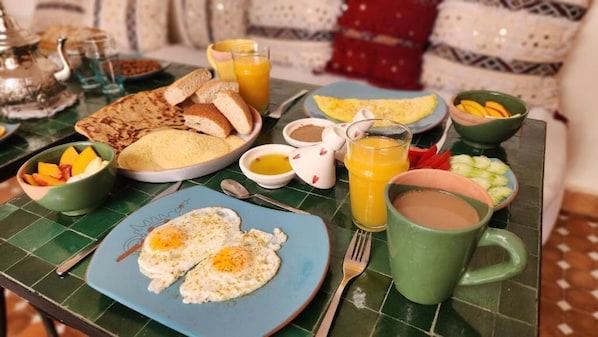 A breakfast table with eggs, toast, fruit, and beverages.