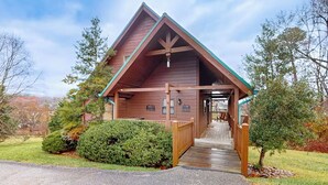 A wooden lodge with a covered porch and a stone pathway leading to the entrance.