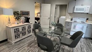 Une cuisine moderne avec un coin repas, comprenant une table en verre, des chaises grises et un meuble dont le design est décoratif.
