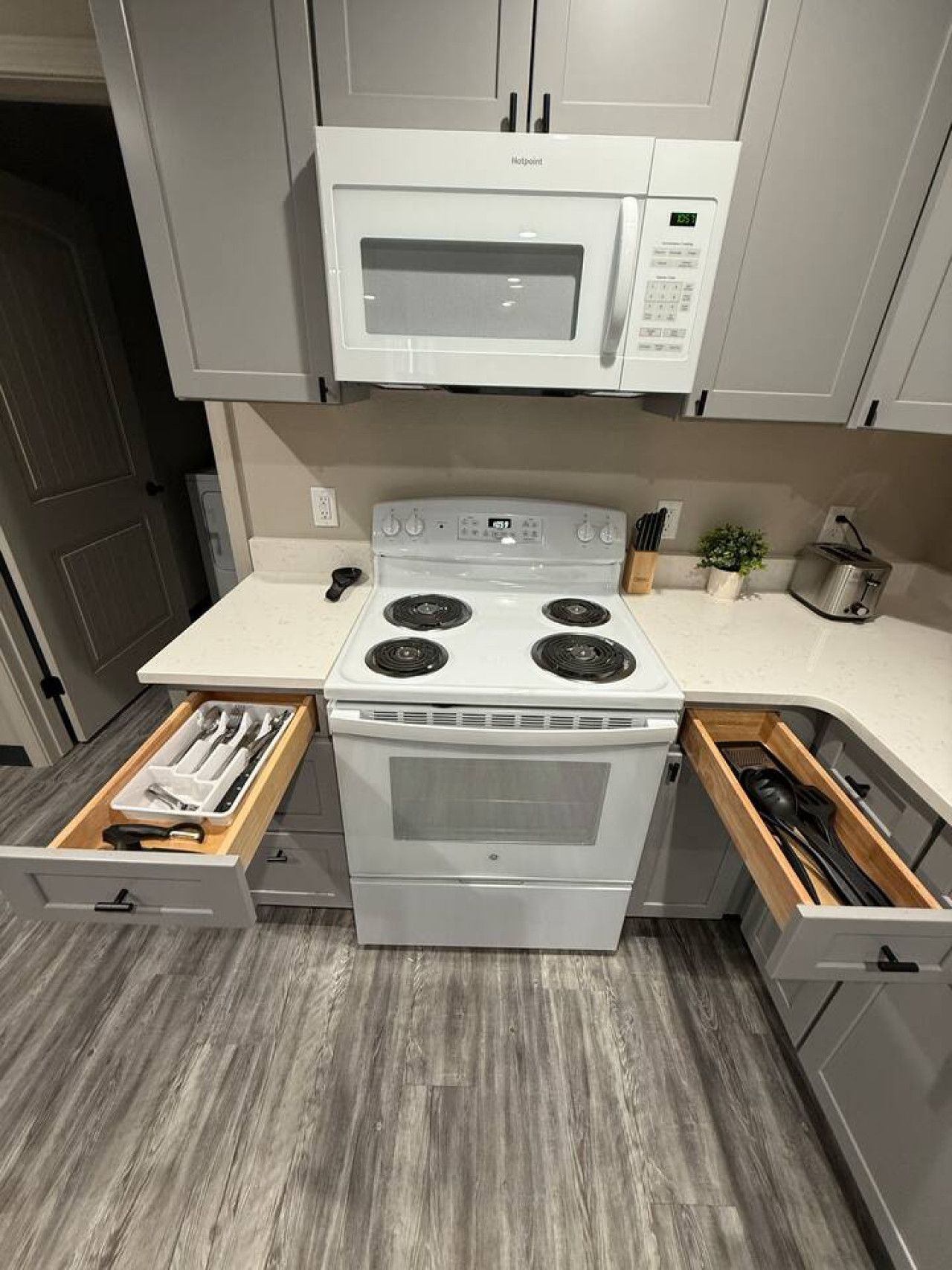 Una cocina compacta con microondas, estufa y cajones de almacenamiento integrados.