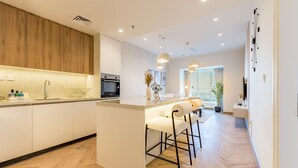 A modern kitchen with a central island, bar stools, and a dining area with a large window.