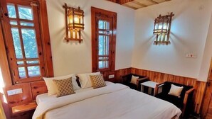 Un dormitorio tipo cabaña de madera con una cama grande, dos mesitas de noche y dos faroles fijados a la pared.