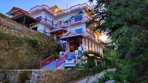 Un edificio de varios pisos con una escalera de piedra que conduce a un coche estacionado frente a él.