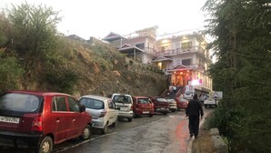 Un estacionamiento con varios autos estacionados a lo largo de una calle, que conduce a un edificio de varios pisos y balcones.