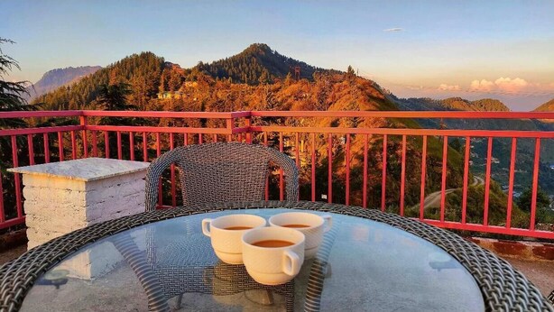 Un balcón con mesa y sillas, con vistas a un paisaje montañoso.
