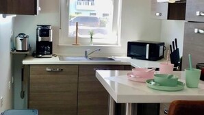 Una cocina compacta con armarios de madera, un lavamanos de acero inoxidable y un ventanal que proporciona luz natural.