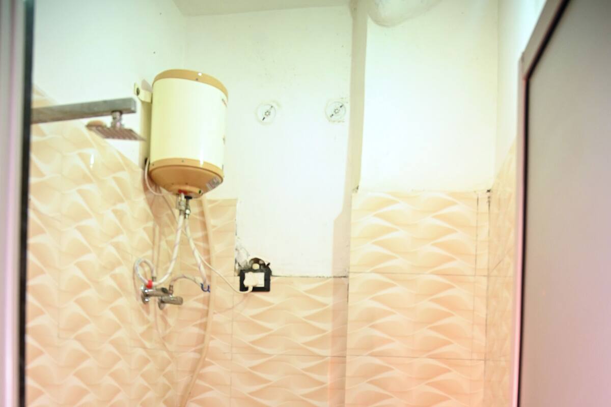 A small, compact bathroom with a toilet, a shower, and a toilet paper holder.